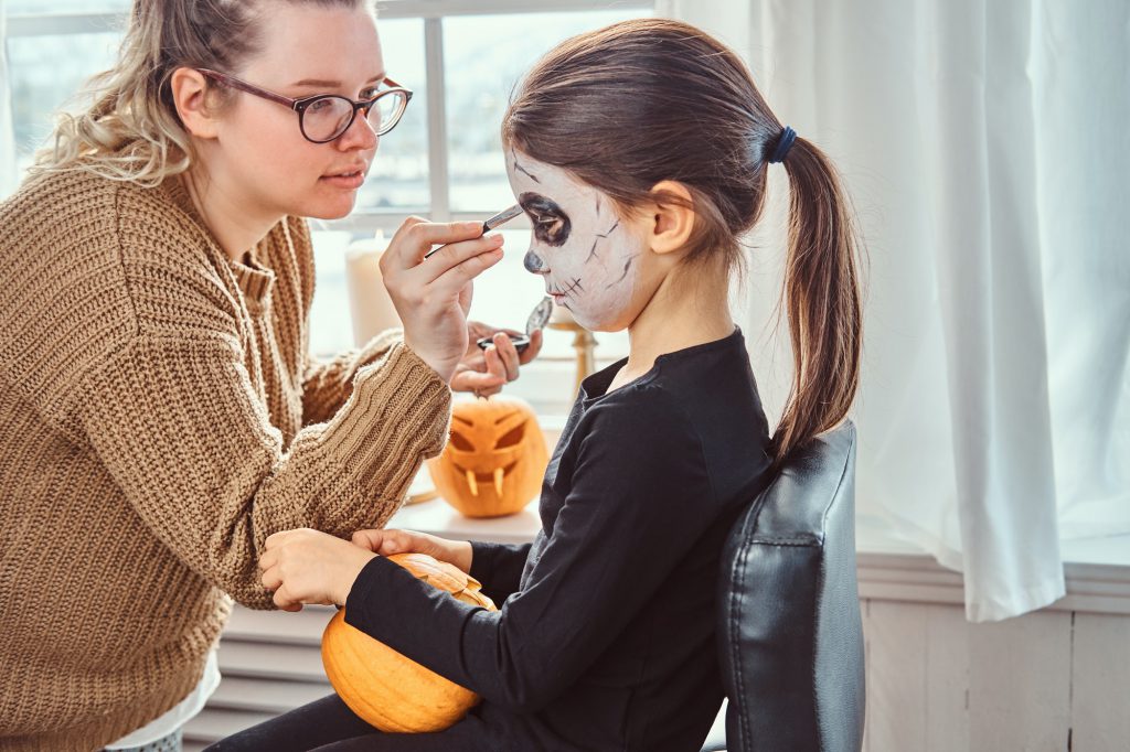 mom painting daughter face for halloween party